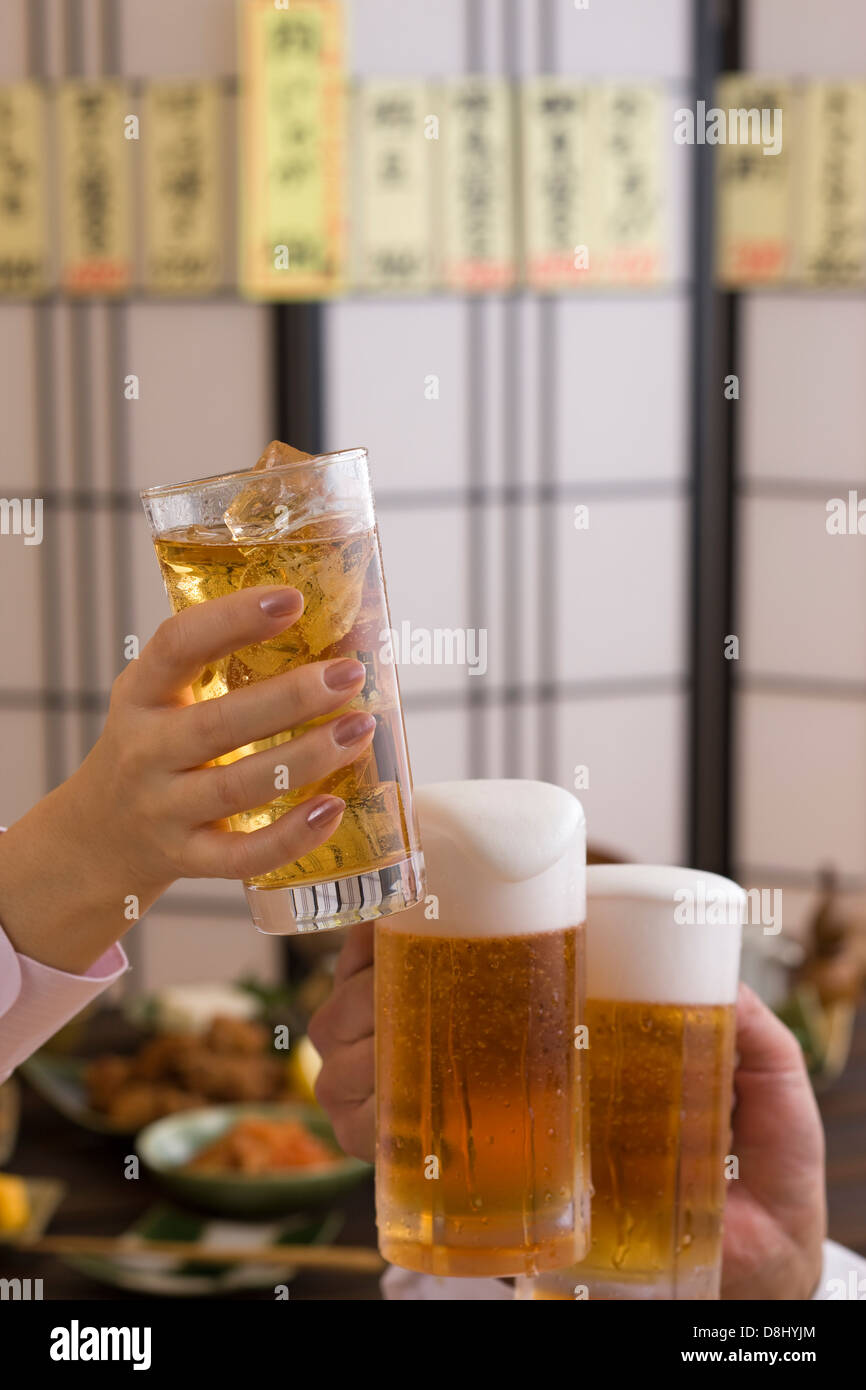Trois personnes Toasting avec bière et Chu-Hi à Izakaya Banque D'Images