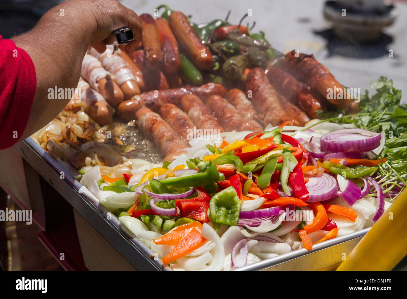 Street-food vendor-bacon cuisson enveloppé de hot dogs, oignons, poivrons et piments habanero durant Carnaval festival. Banque D'Images