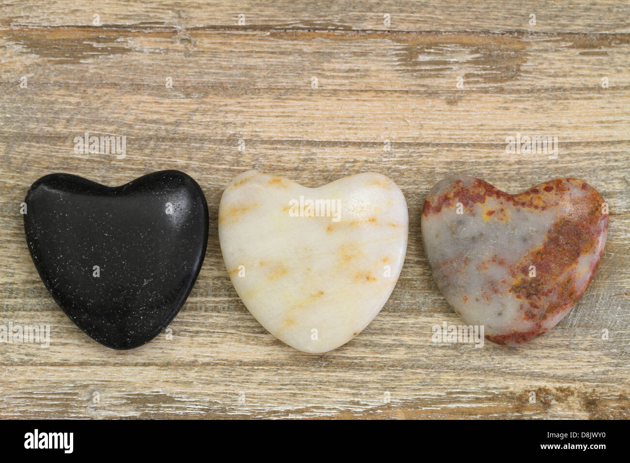 Blanc, noir et brun des pierres en forme de coeur sur fond de bois Banque D'Images