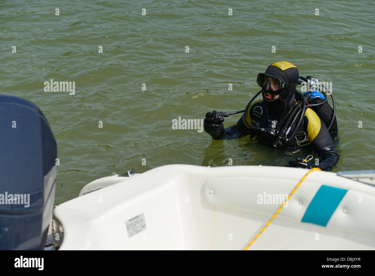 Diver venant hors de l'eau à côté d'un bateau à moteur Banque D'Images