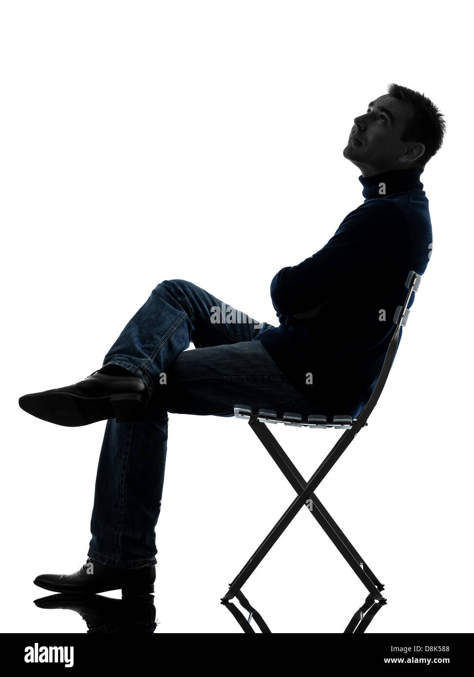 Un homme assis à la pleine longueur jusqu'en silhouette studio isolé sur fond blanc Banque D'Images