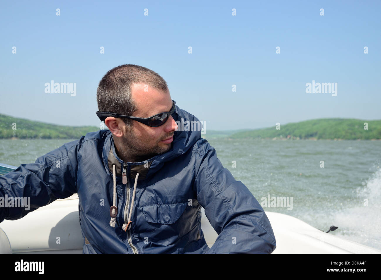 L'homme dans un bateau à moteur à l'accélération le long de la rive, tenant serré et contrôler les vagues Banque D'Images