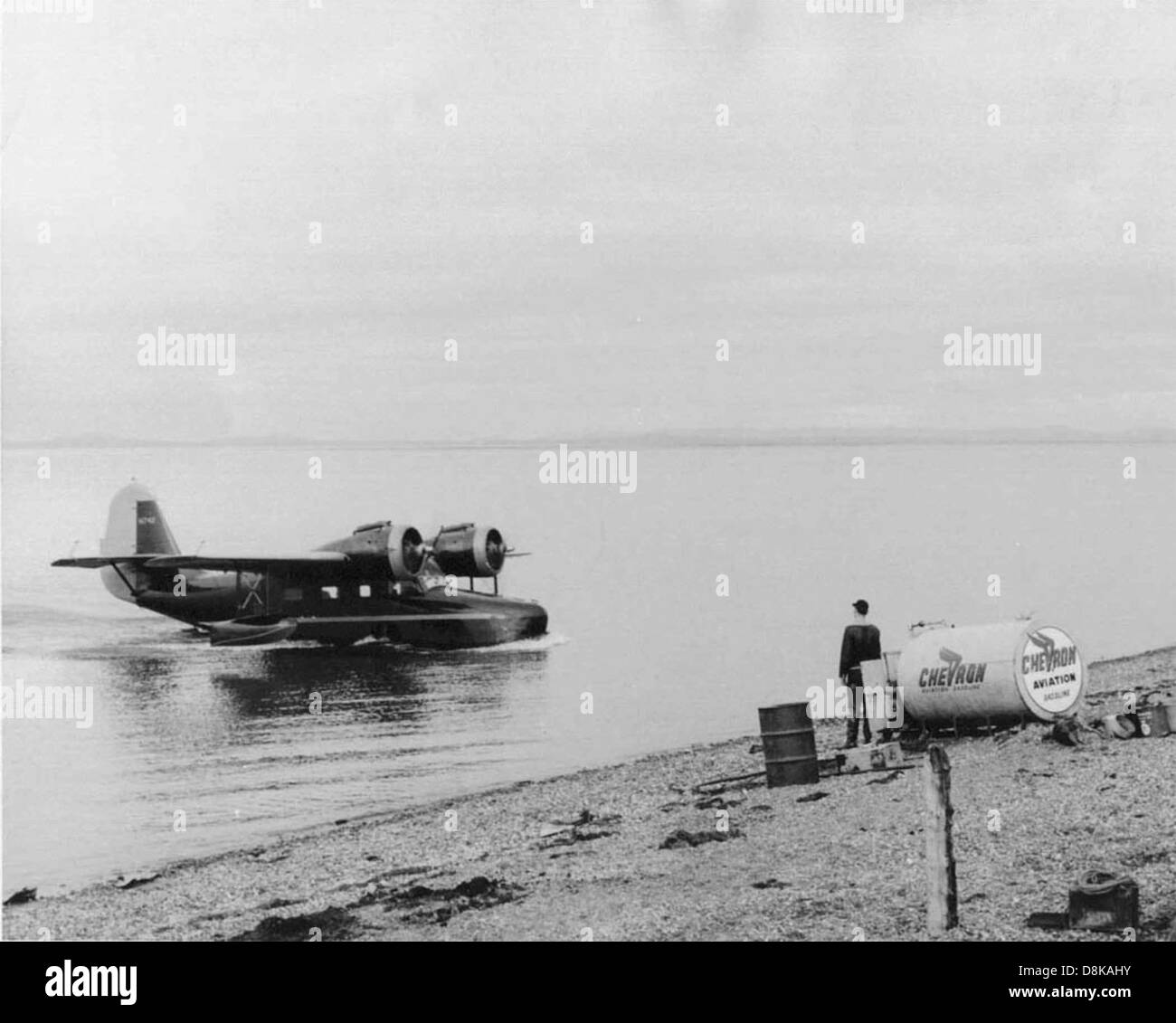 Une photo vintage montrant un vieil avion survolant ou près d'une rivière, capturant l'essence de l'aviation précoce. La rivière en contrebas et l’aspect altéré de la photographie mettent en évidence le passage du temps et l’histoire du vol. Banque D'Images