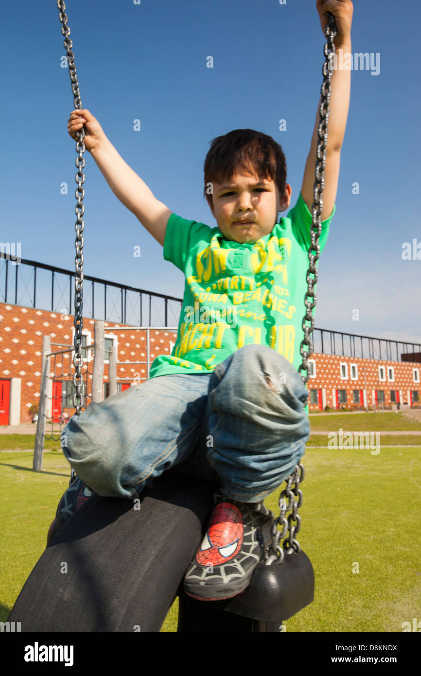 Les enfants jouent sur des balançoires en face de maisons à Almere avec panneaux solaires photovoltaïques sur le toit. Banque D'Images