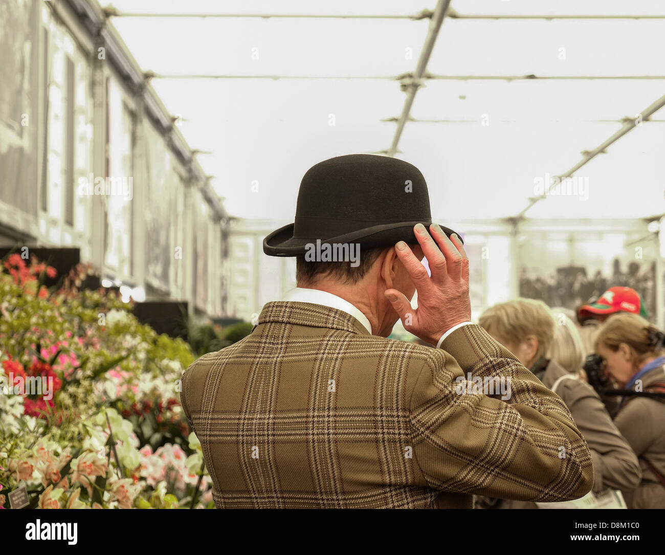 Un homme qui ajuste son chapeau de melon au Chelsea Flower Show à Londres, au Royaume-Uni. Banque D'Images