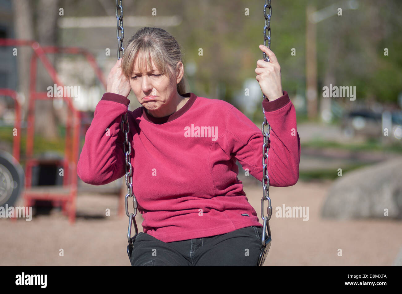 Femme avec expression malheureuse assis sur une balançoire. Banque D'Images