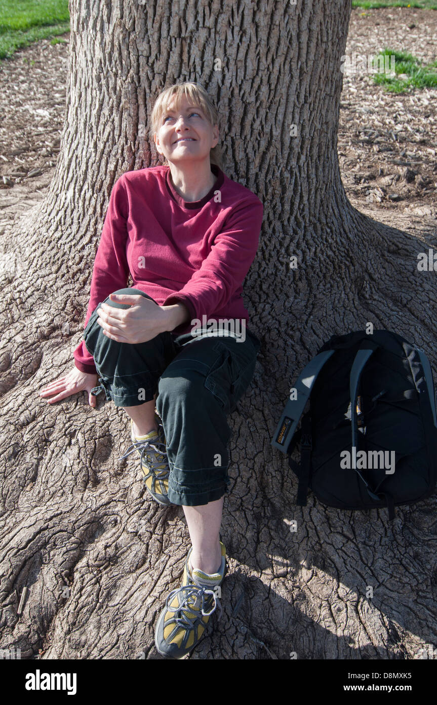 Femme assise sous un arbre, et souriant. Banque D'Images