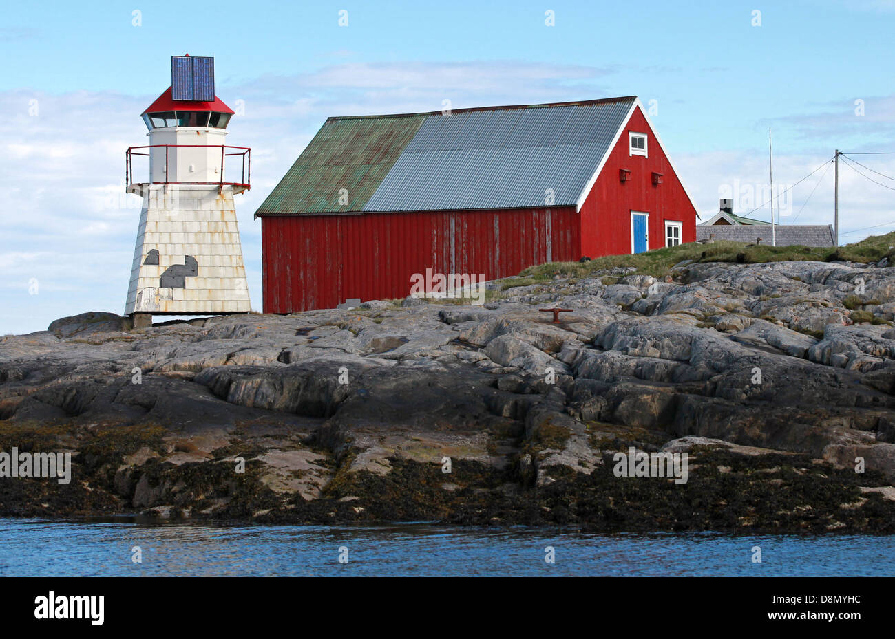 Phare norvégien. Tour blanche rouge haut se dresse sur les rochers côtiers traditionnels à proximité maison en bois rouge Banque D'Images