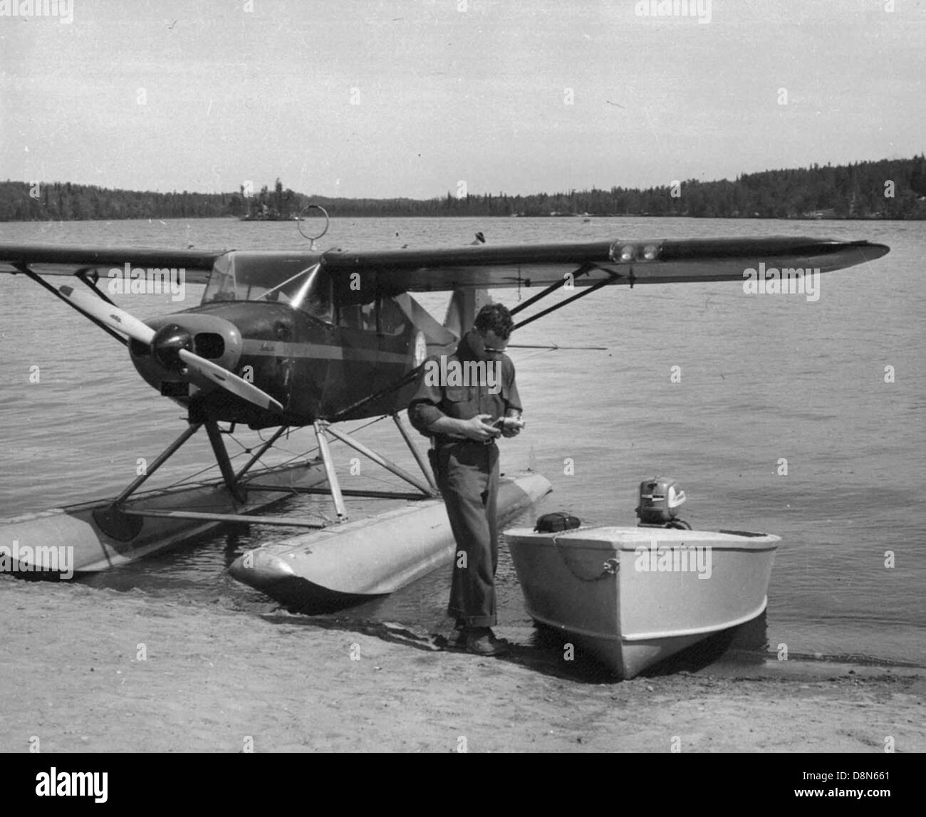 Cette image montre un agent en forme de croix et un hydravion décollant du lac Louise, entourés de magnifiques paysages alpins. L'avion est conçu pour le décollage d'eau, mettant en évidence sa polyvalence dans des endroits éloignés. Banque D'Images