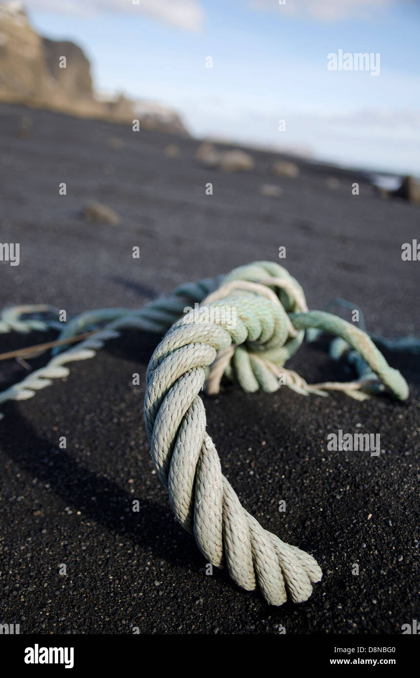 Green corde posée sur une plage de sable noir, l'Islande Banque D'Images