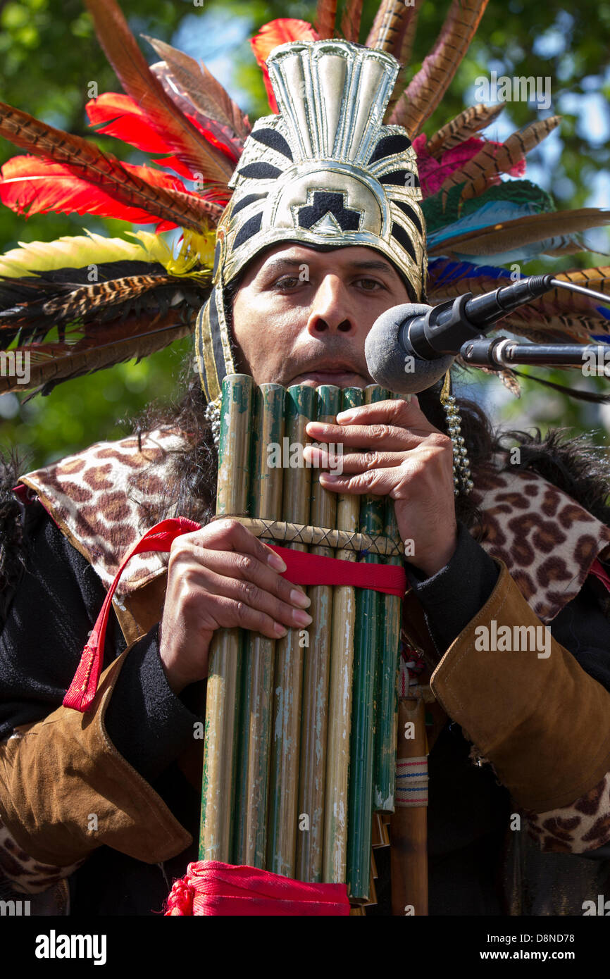 Manchester, UK. 1er juin 2013. Sergio Fistely (MR) un artiste de rue en Aztec Indian Native American costume et coiffe de plumes à Manchester Piccadilly appréciant les diverses attractions du centre-ville avec des amuseurs de rue, rue en costume muscians, jouer un accompagnement musical. Pan flutes de pan, syrinx, flûte sont un groupe d'instruments de musique fondé sur le principe de la tube fermé, composé de plusieurs tuyaux d'augmenter progressivement la longueur. Plusieurs variétés de panflutes ont longtemps été populaires comme instruments folkloriques. Les tuyaux en bois sont généralement fabriqués à partir de bambou, ou de la canne à sucre. Banque D'Images