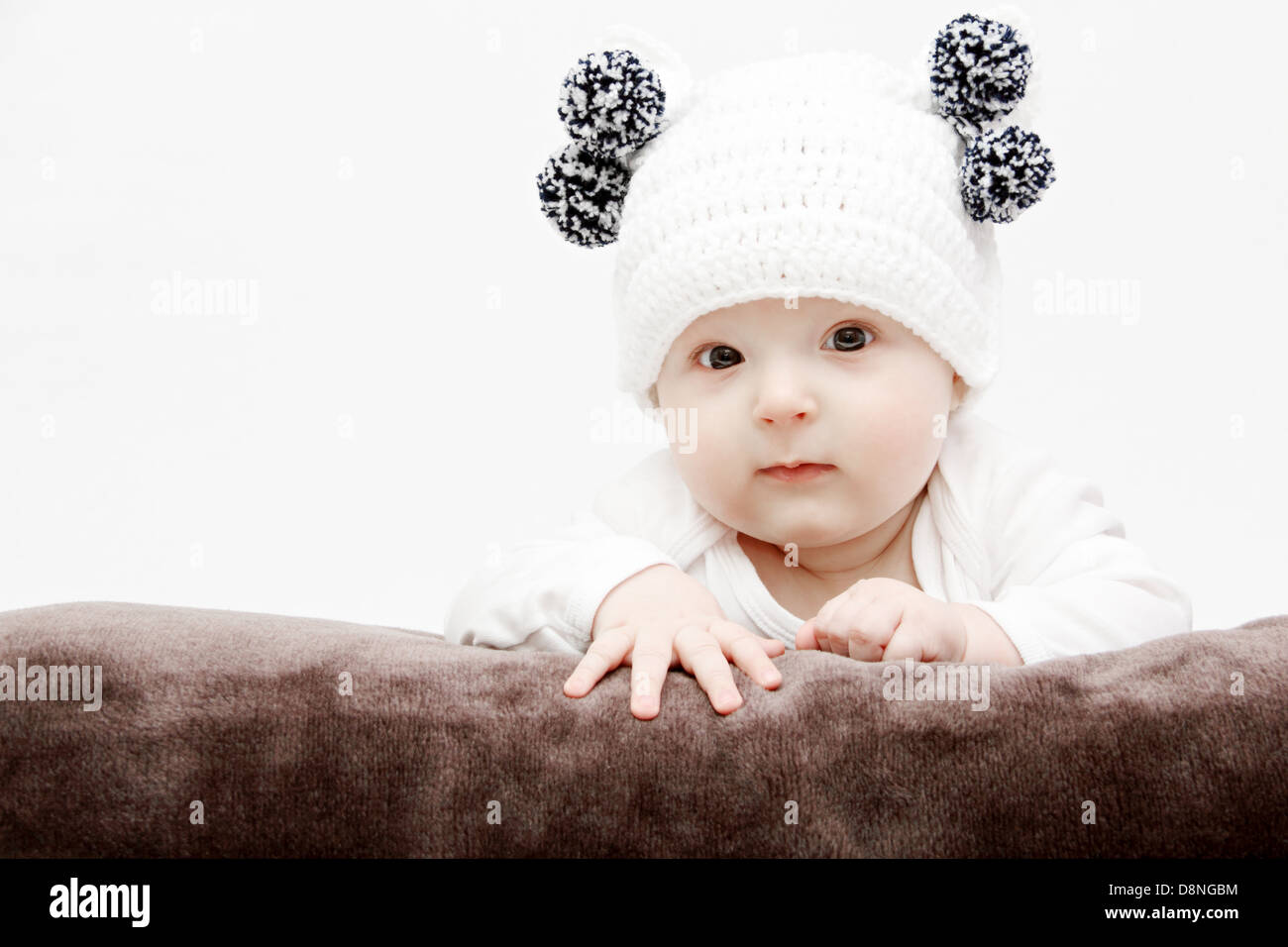 Bébé en blanc hat se trouve sur le lit Banque D'Images