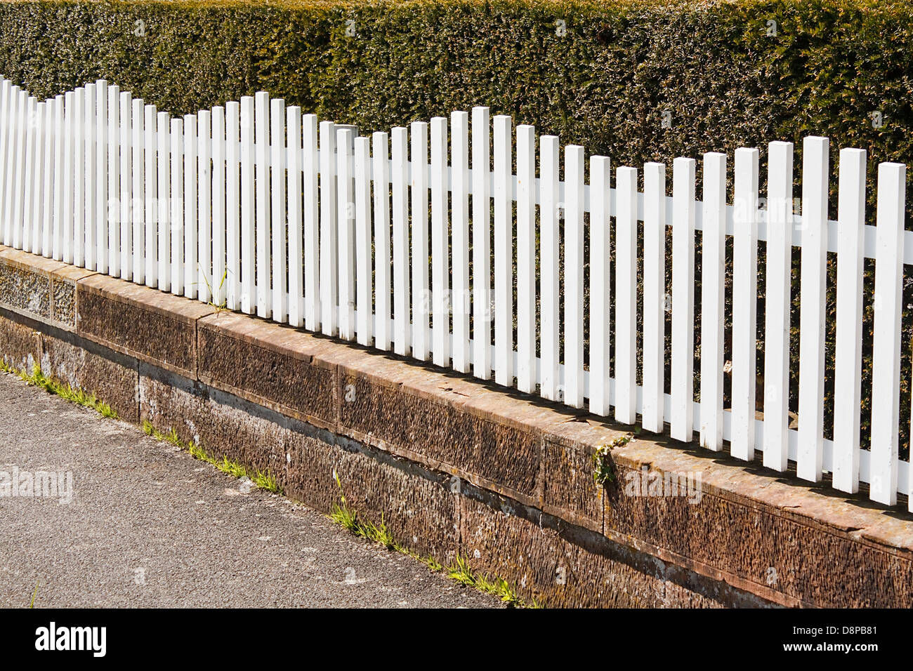 Clôture blanche à côté de pathway avec bush derrière Banque D'Images