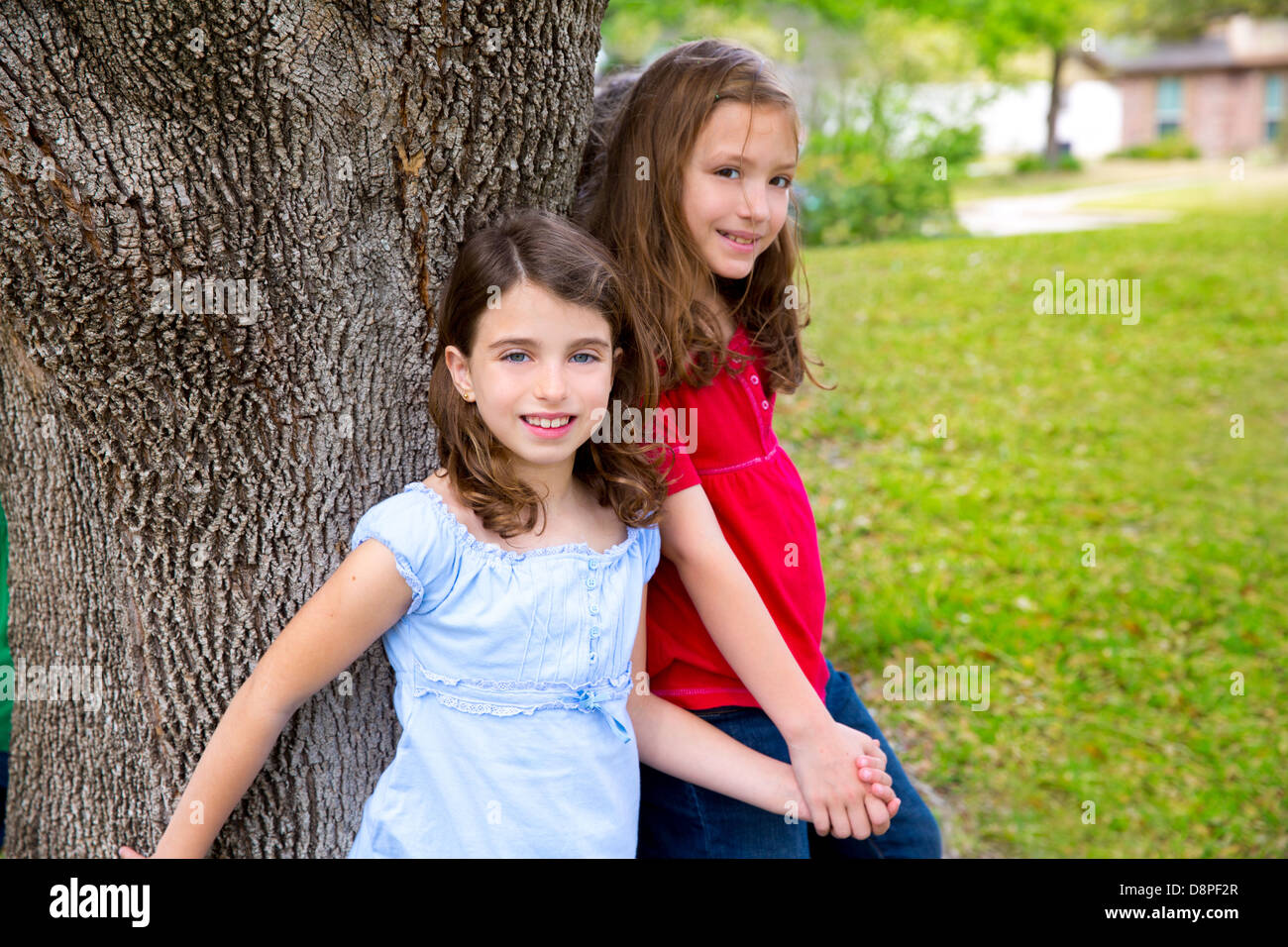 Groupe enfants filles ami amis jouant sur le tronc de l'arbre à l'extérieur du parc Banque D'Images