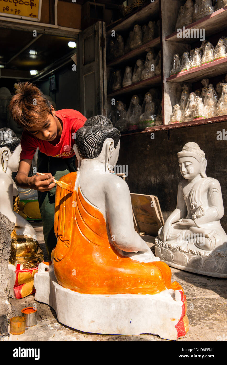 Peinture d'un jeune homme birman en effigie de Bouddha statue dans le district de l'atelier de marbre Mandalay Birmanie Myanmar Banque D'Images