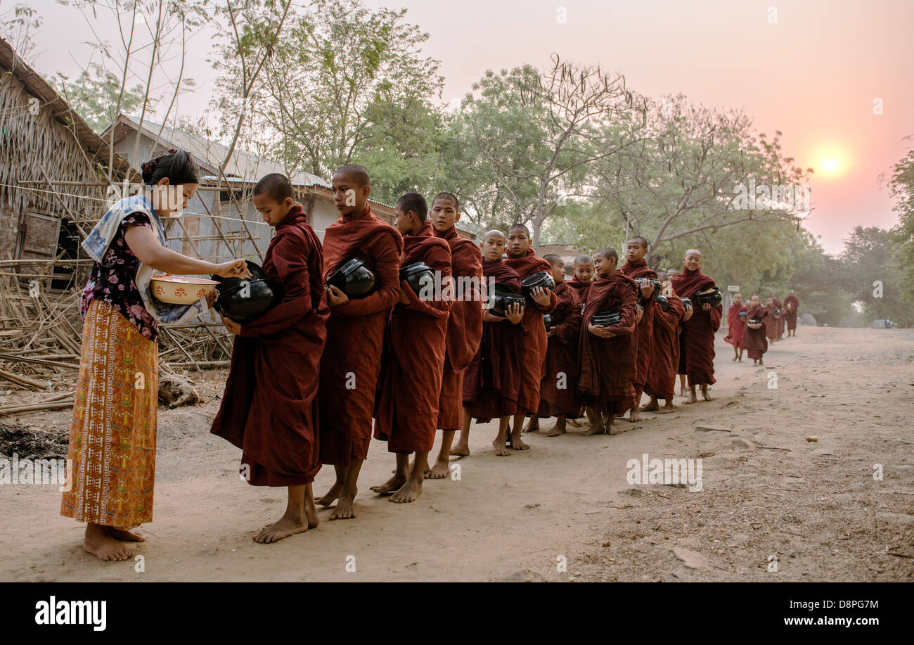 Les moines bouddhistes, la collecte de l'aumône de bols de nourriture dans la matinée des villageois près de Bagan Birmanie Myanmar Banque D'Images