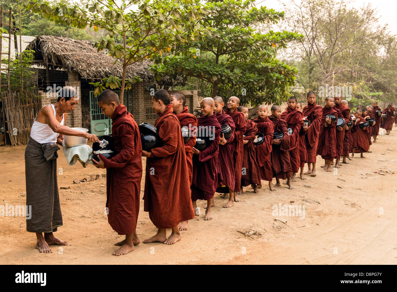 Les moines bouddhistes, la collecte de l'Aumône (ou boules) de nourriture dans la matinée des villageois près de Bagan Birmanie Myanmar Banque D'Images