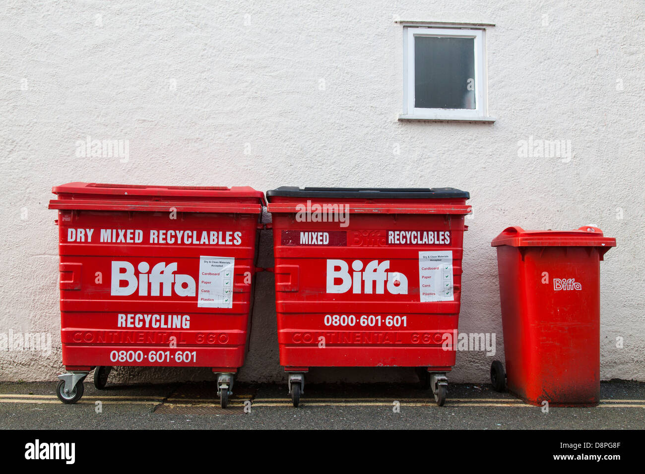 Rangée de bacs de recyclage rouge contre un mur peint. Banque D'Images