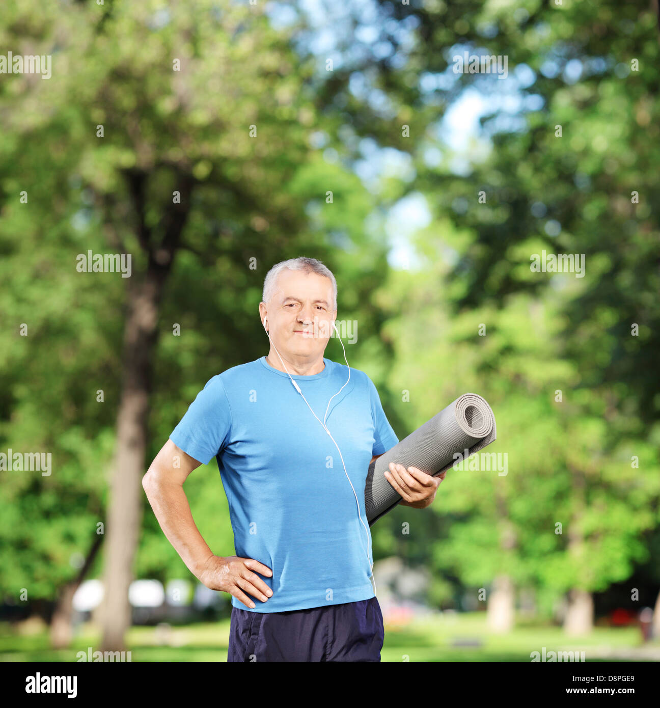 Smiling mature man holding un exercice de mat in park Banque D'Images