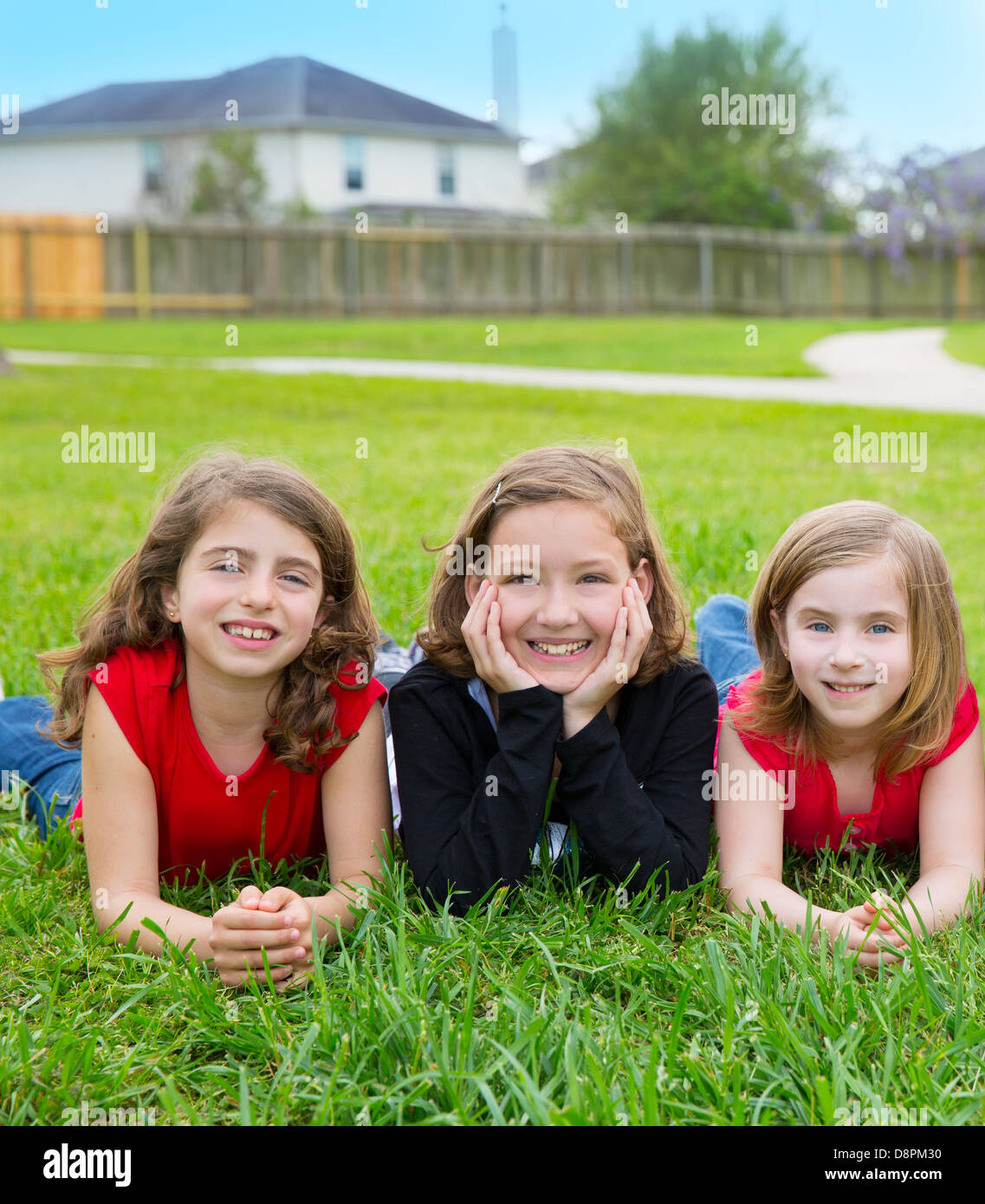 Groupe de filles enfants allongés sur l'herbe pelouse smiling heureux ensemble dans une rangée Banque D'Images