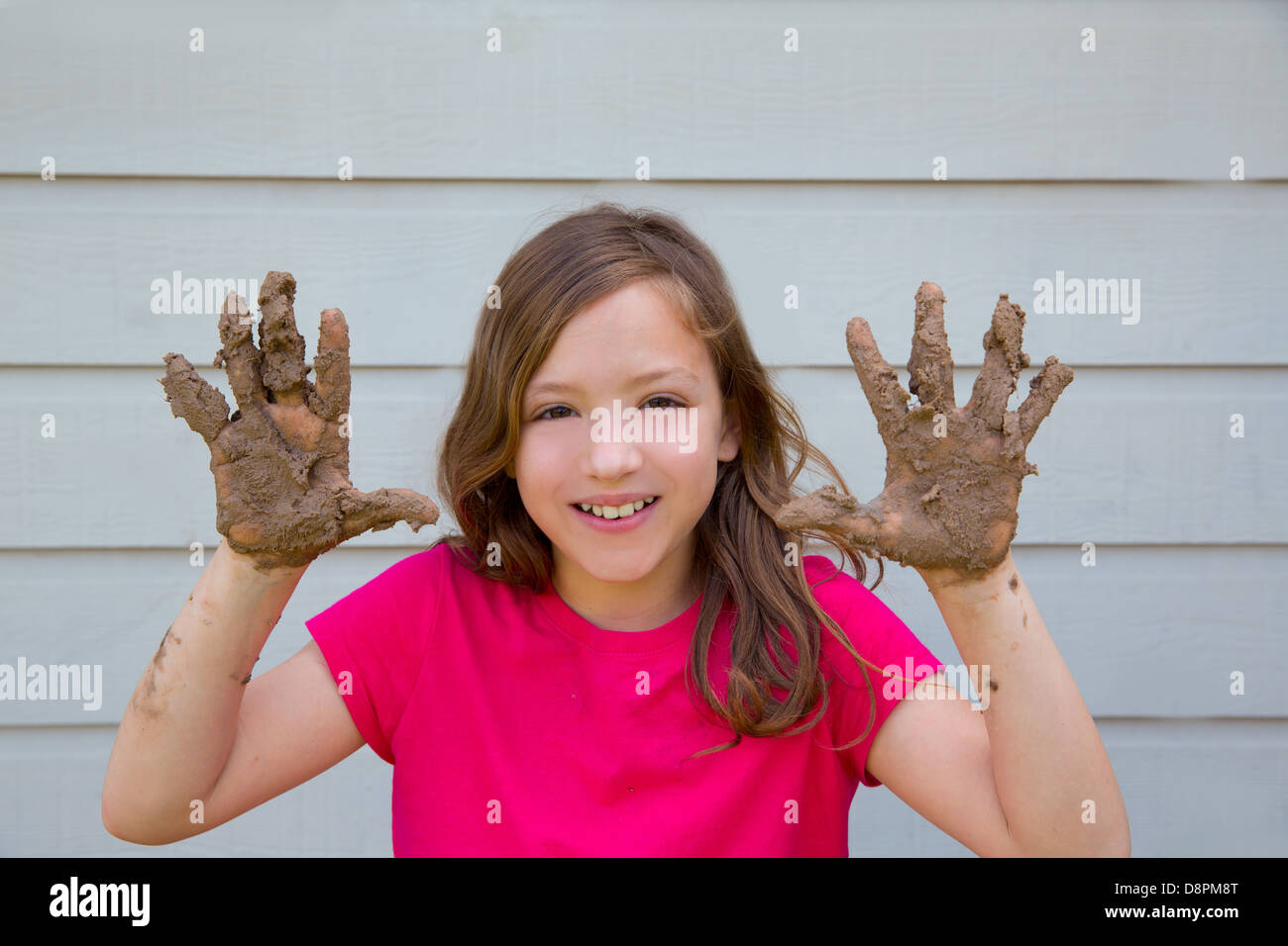 Happy kid fille jouant avec de la boue avec des mains sales smiling portrait Banque D'Images