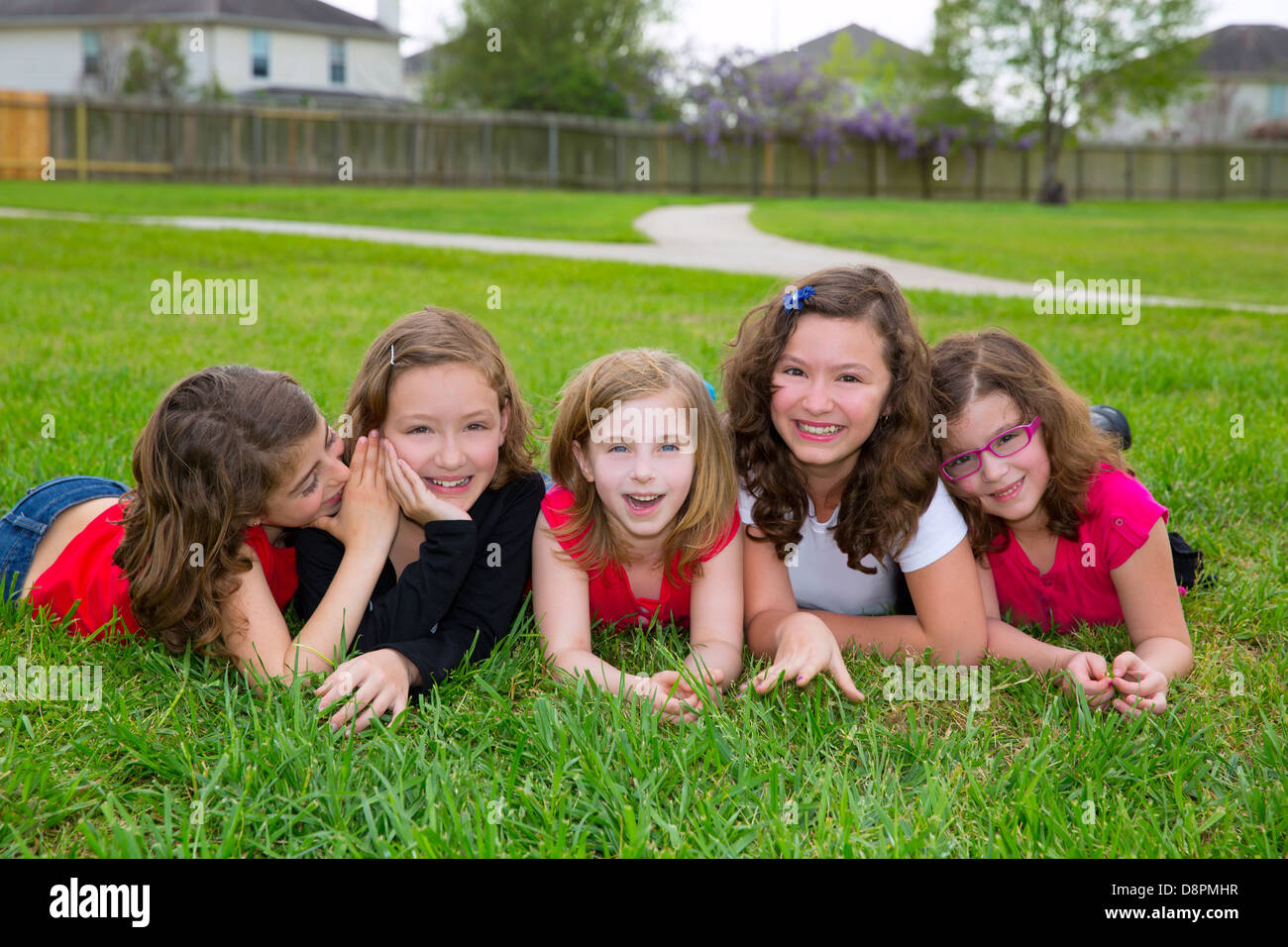 Groupe de filles enfants allongés sur l'herbe pelouse smiling heureux ensemble dans une rangée Banque D'Images