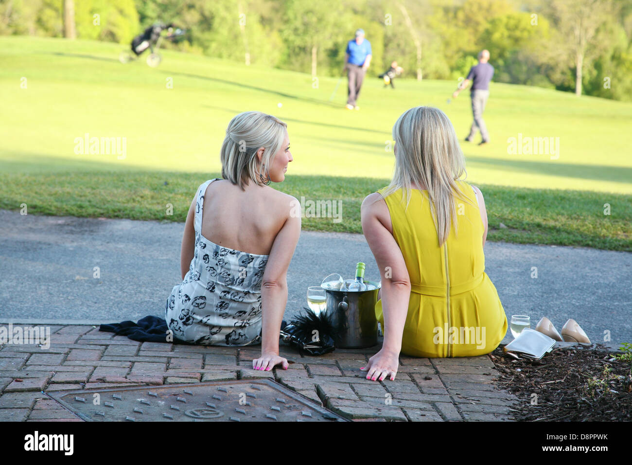 Deux jeunes femmes s'assit en prenant un verre, tout en regardant les golfeurs putt au Celtic Manor, au Pays de Galles, Royaume-Uni. Banque D'Images
