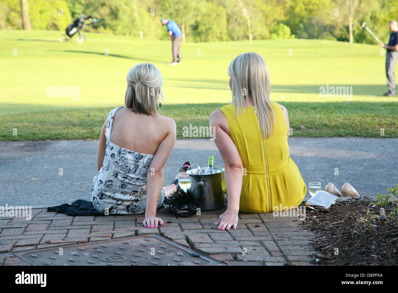 Deux jeunes femmes s'assit en prenant un verre, tout en regardant les golfeurs putt au Celtic Manor, au Pays de Galles, Royaume-Uni. Banque D'Images