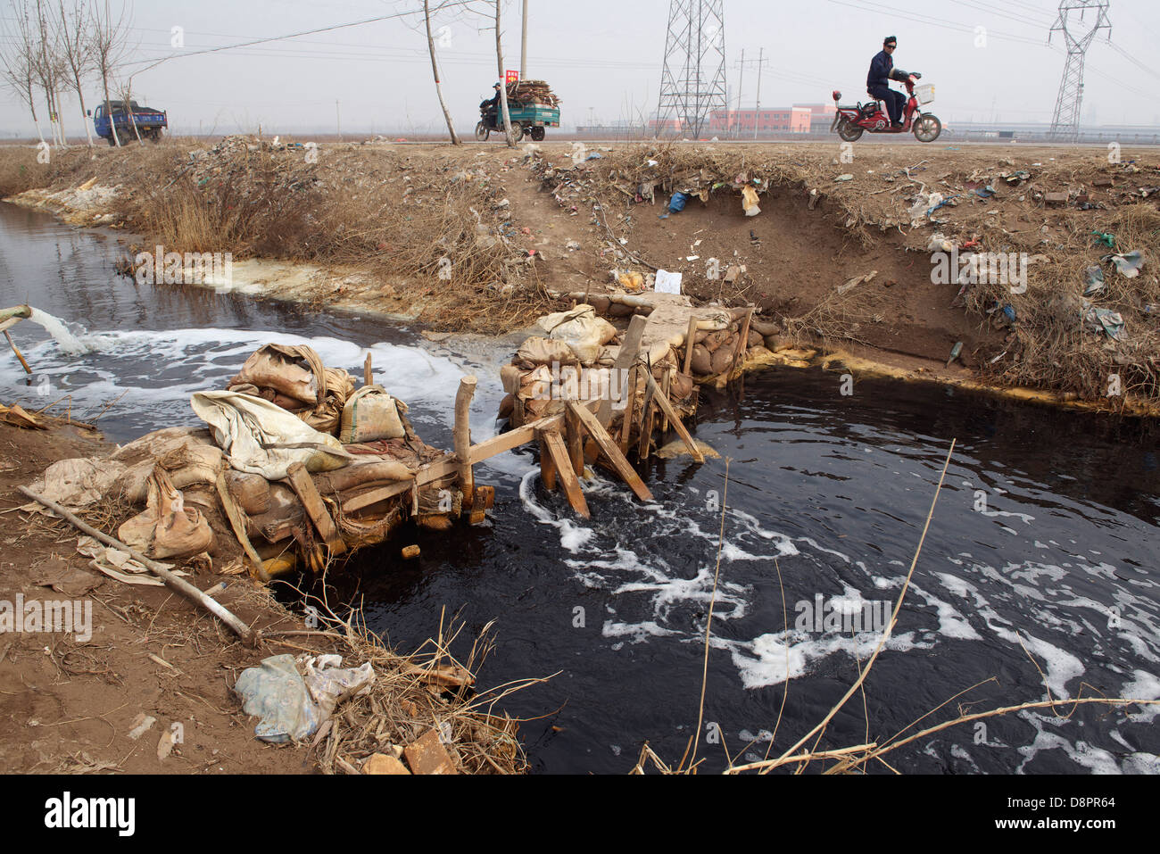 Un fossé sur le terrain devient noir par l'eau des déchets industriels dans les usines de la ville de XinAn, Beijing, Chine. 2013 Banque D'Images
