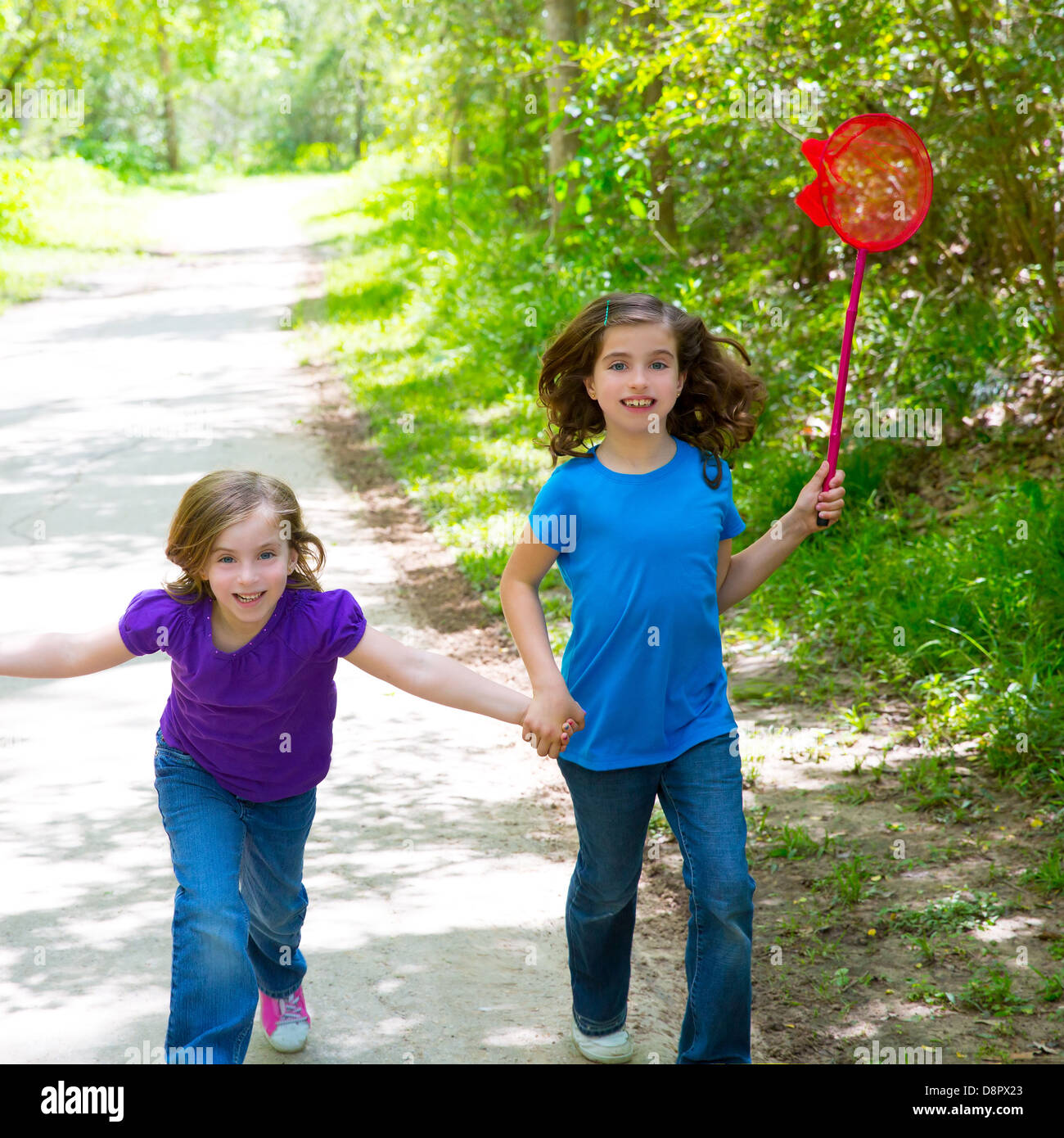 Les amis et ma soeur filles exécutant dans la piste en forêt smiling happy avec butterfly net Banque D'Images