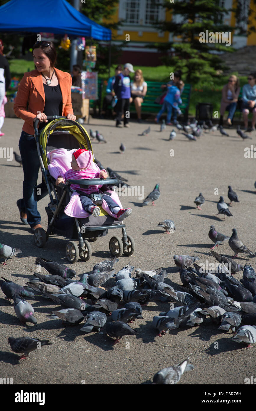 Enfant fille et maman jouant avec des colombes dans la ville street Banque D'Images