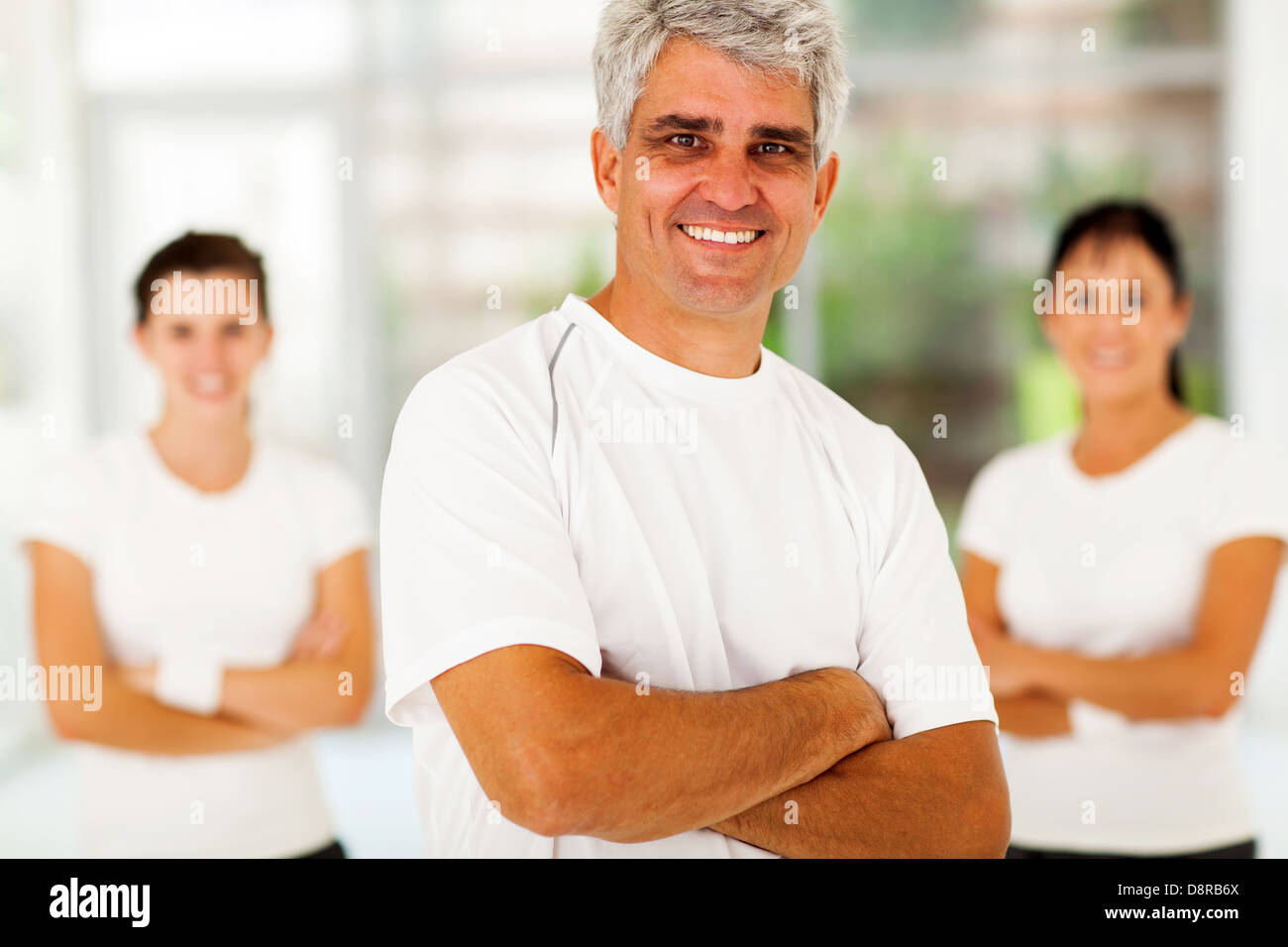 Smiling middle aged man sportive avec les bras croisés en face de famille à la maison Banque D'Images