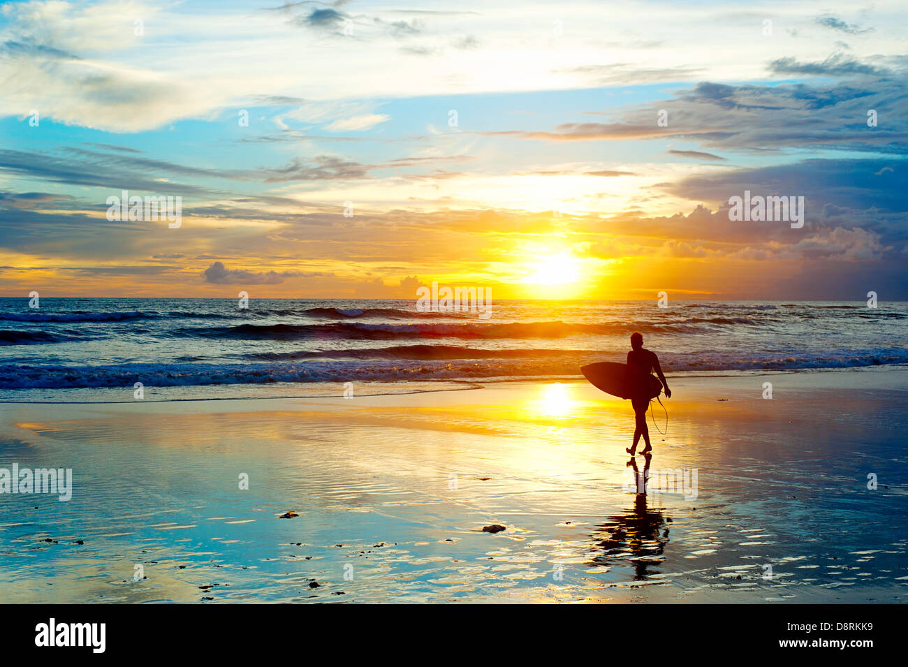 Surfeur sur la plage au coucher du soleil sur l'île de Bali, Indonésie Banque D'Images