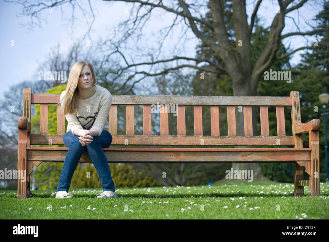 Une jeune femme assise sur un banc de parc par elle-même Photo Stock - Alamy