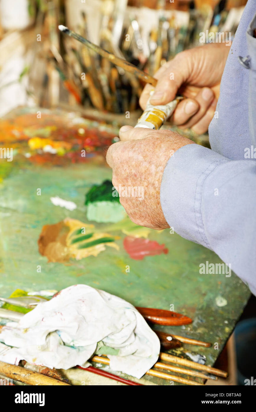 Tube de peinture avec les mains du peintre Banque D'Images