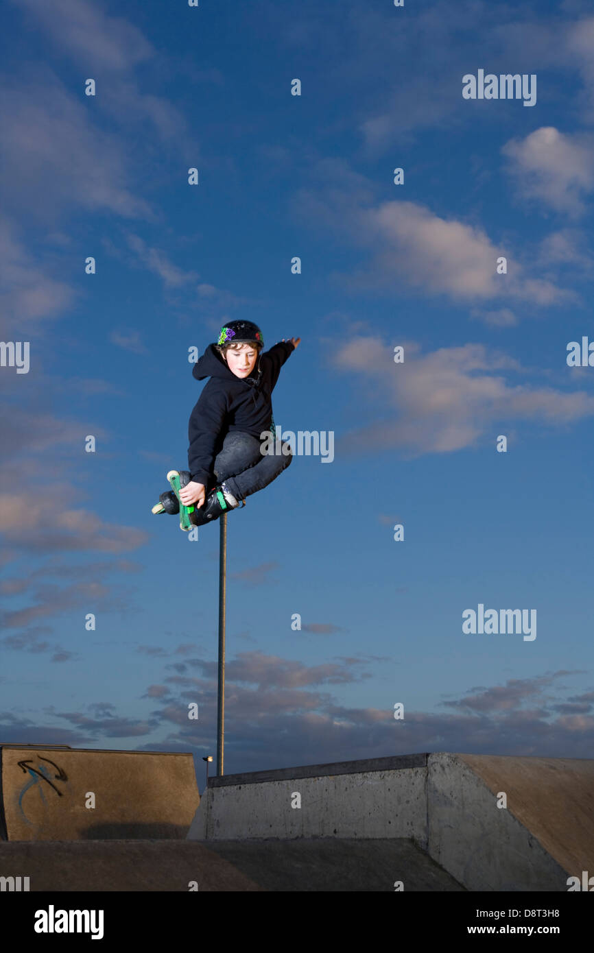 Les jeunes Inline Skater sautant dans un skate park. Banque D'Images