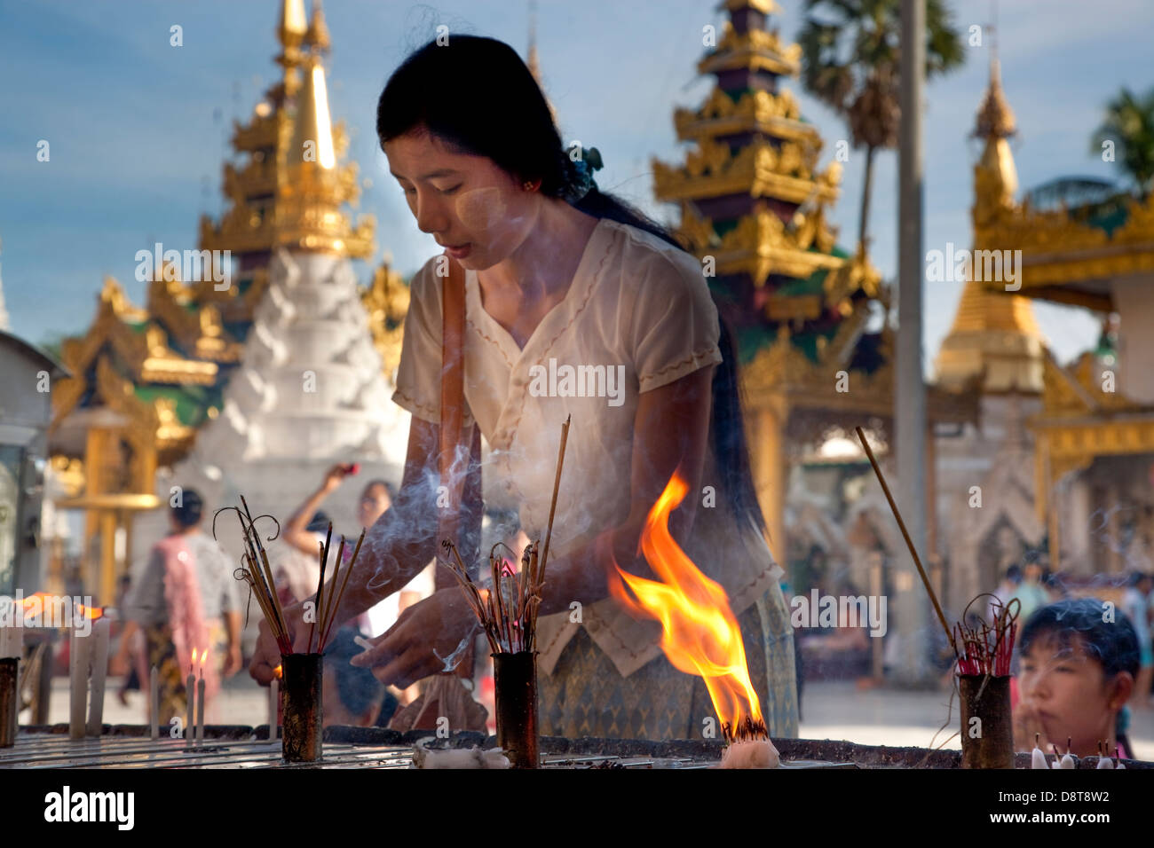 Dans le complexe du temple bouddhiste Schwedagon à Rangoon (Yangon) une femme se concentre sur la préparation d'un bâton d'encens. Banque D'Images
