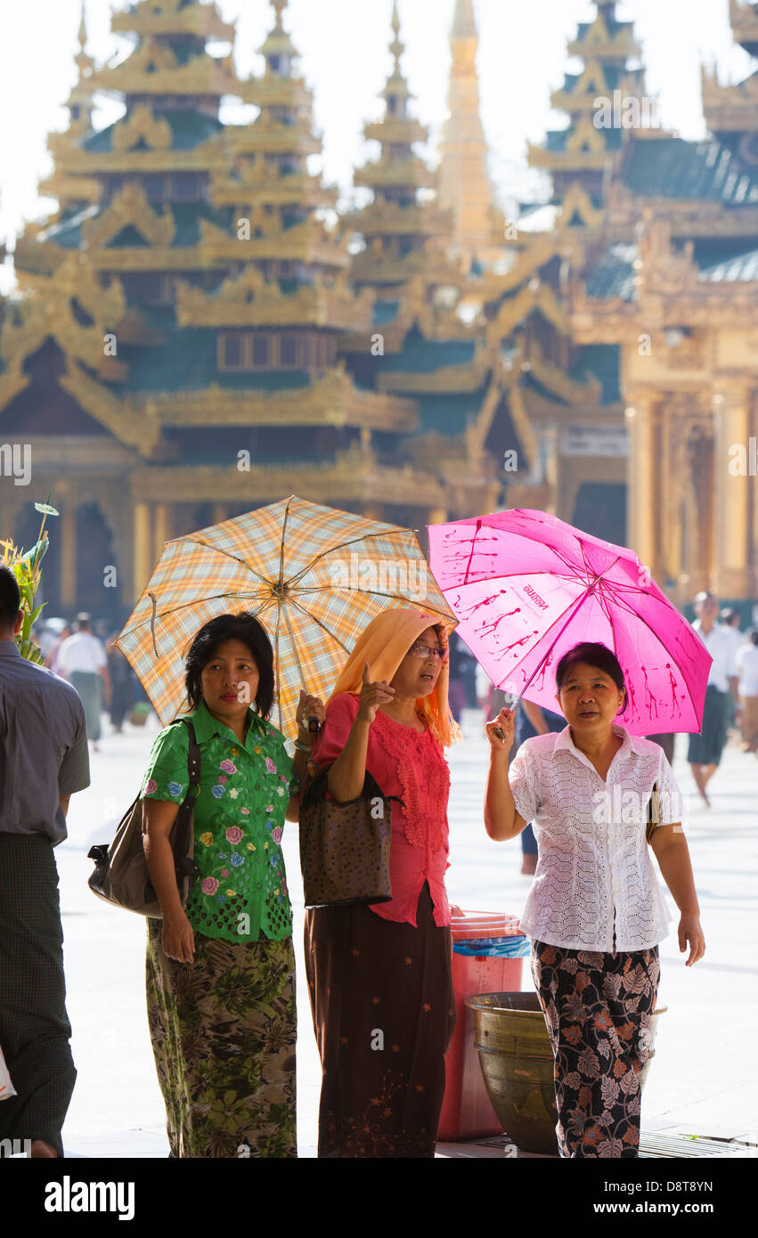 Trois femmes semblent être de décider où aller ensuite dans le temple Schwedagon complexes qu'à l'abri du soleil avec des parasols. Banque D'Images