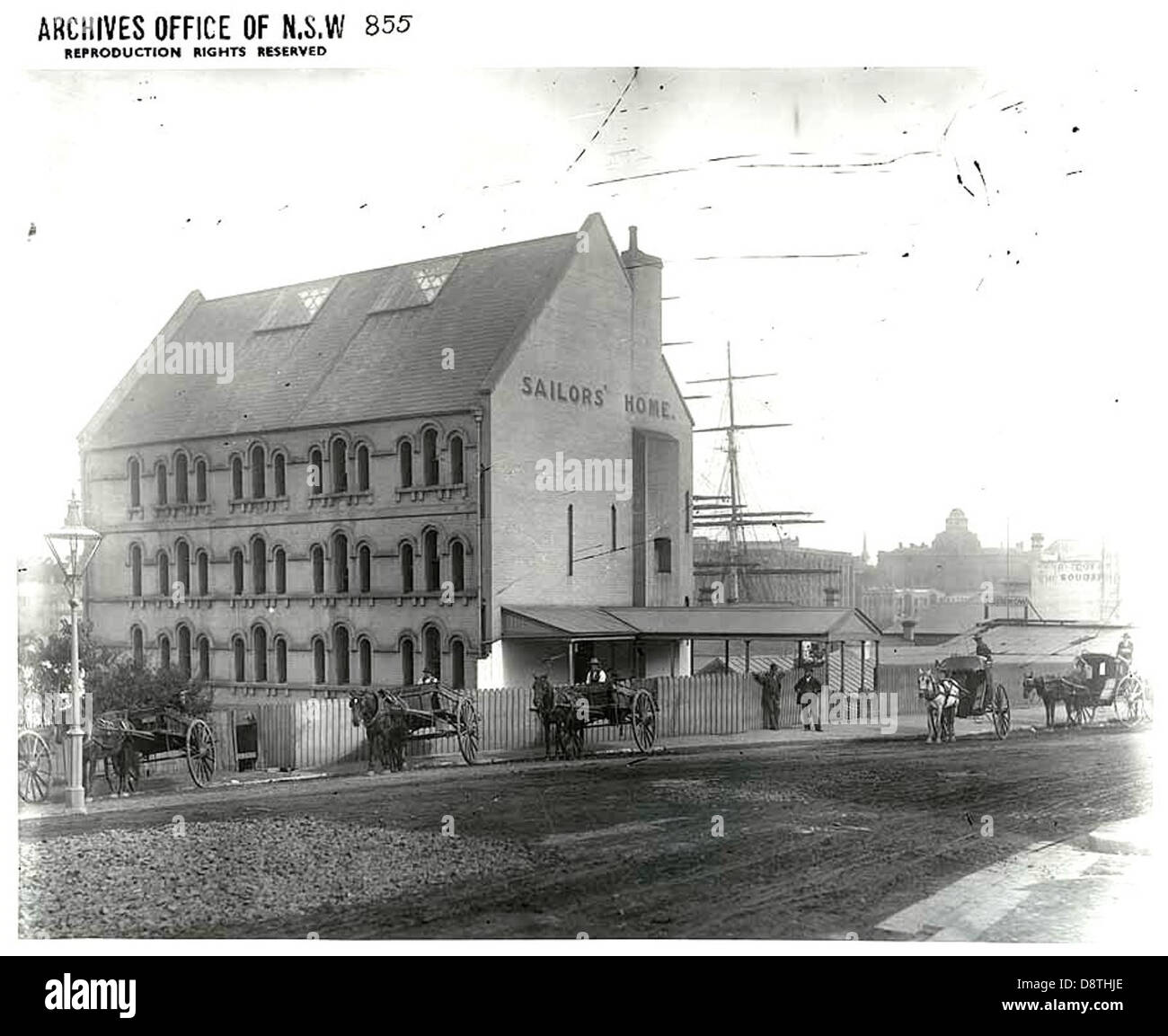 Cette image en noir et blanc capture George Street à The Rocks, Sydney, mettant en valeur le caractère historique de la région. La photographie représente une charrette tirée par des chevaux, reflétant la vie quotidienne à Sydney au XIXe siècle et l'importance des Rocks en tant que quartier historique. Banque D'Images