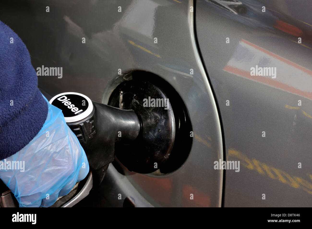 Un gant de protection sur une main d'être montré en diesel de pompage d'un  réservoir de carburant de voiture, dont le prix est à un prix très élevé au  Royaume-Uni Photo Stock -