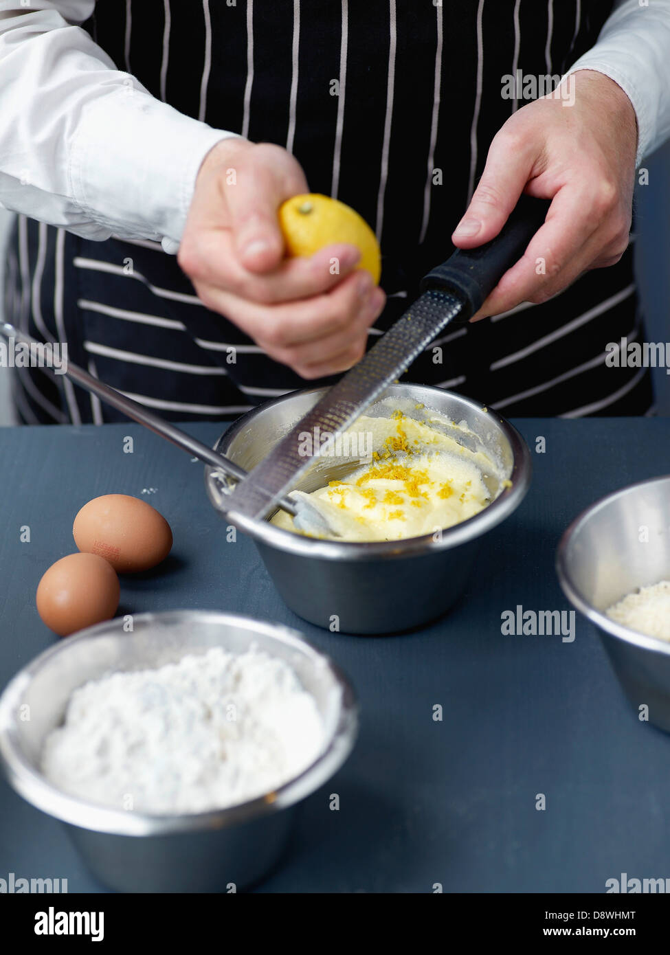 L'ajout du zeste de citron râpé à la pâte à gâteau Banque D'Images