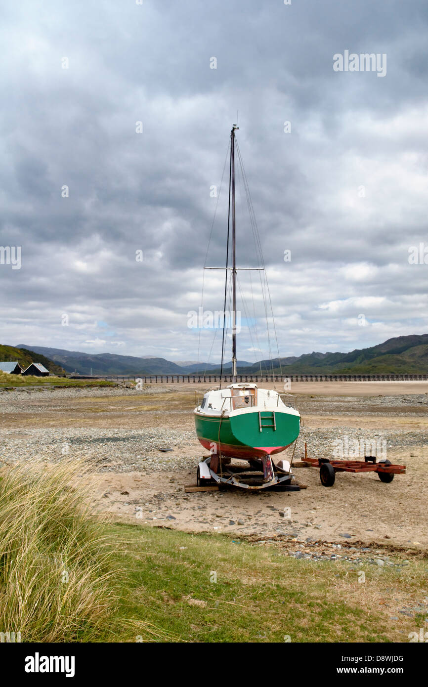 Fairboune Beach sur la côte de la baie de Barmouth, Gwynedd, Pays de Galles, UK avec petit bateau et pont à Barmouth la distance Banque D'Images