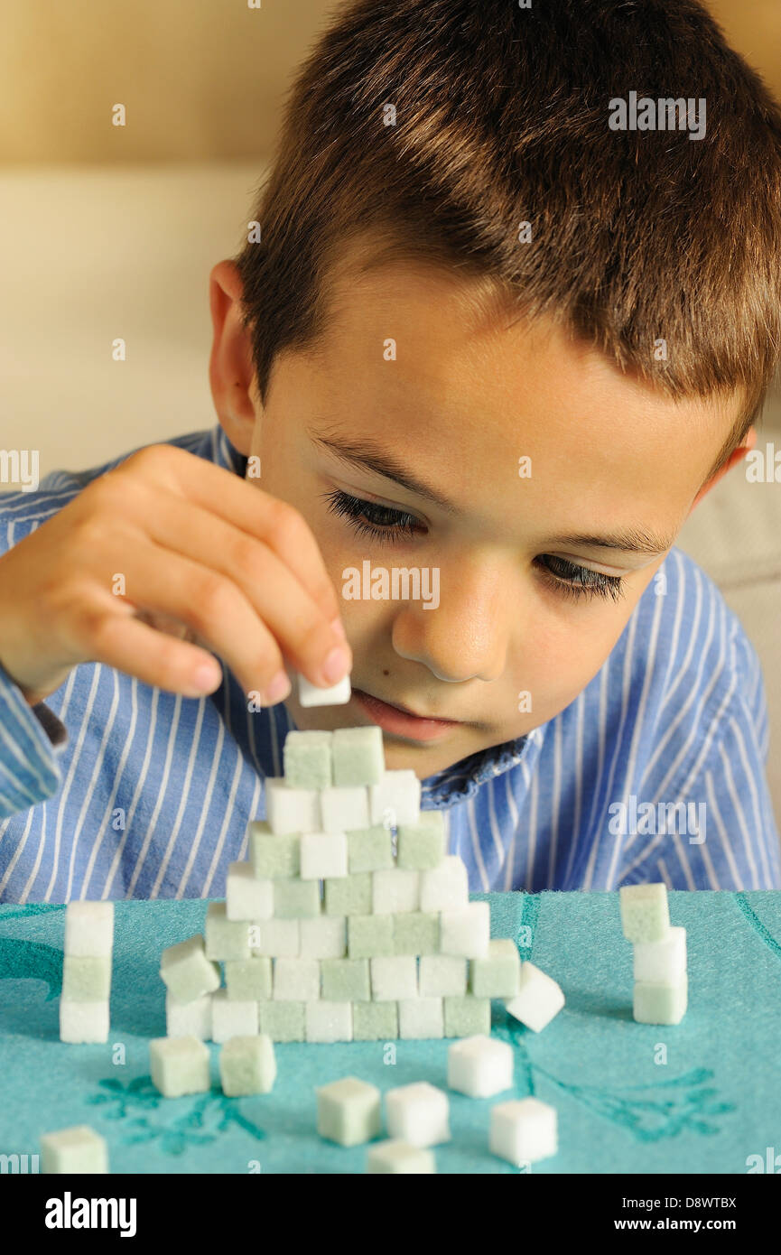 Jeune garçon jouant avec des morceaux de sucre coloré Banque D'Images
