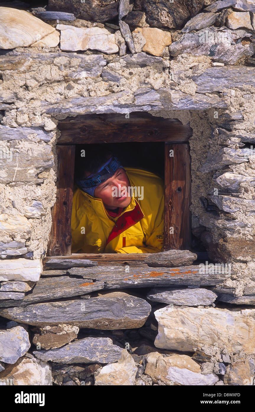 L'homme à la recherche d'une fenêtre dans un bâtiment en pierre. Banque D'Images