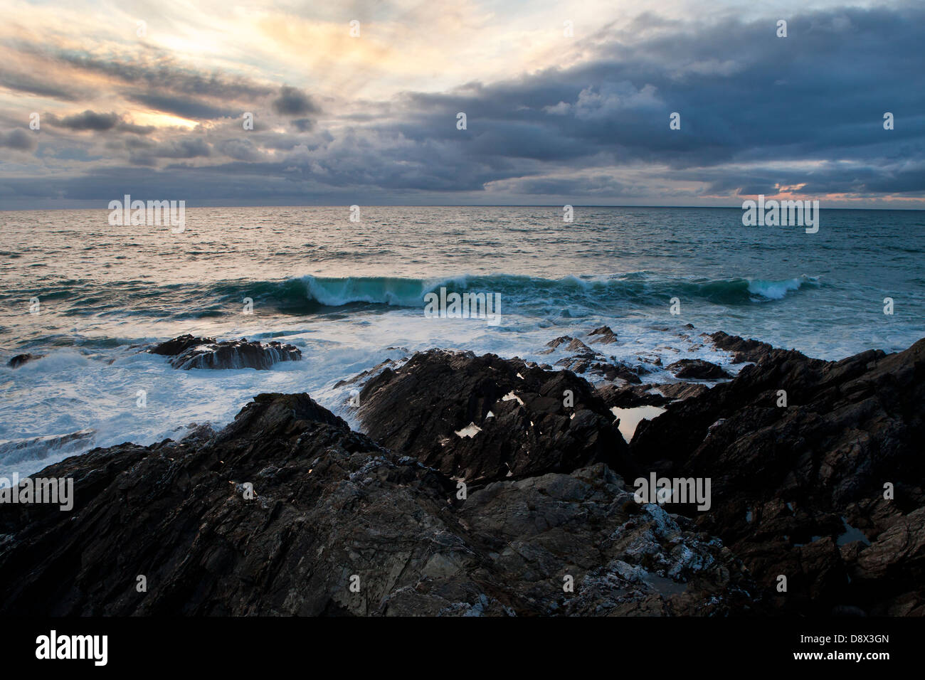 Rouler dans des vagues sur une plage de Newquay soirée orageuse au crépuscule. Banque D'Images