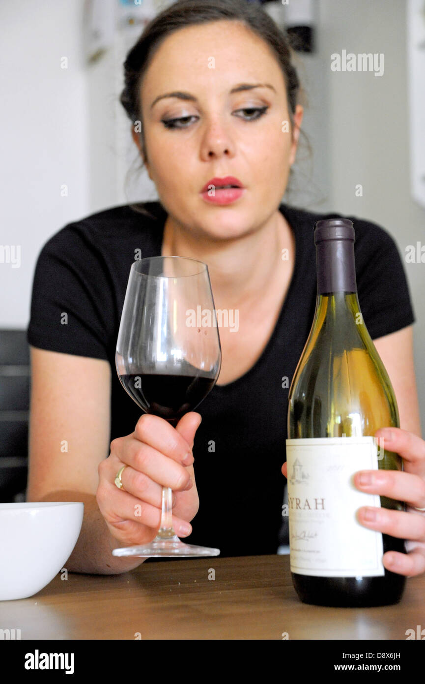 Jeune femme de 20 ans de boire du vin rouge à la triste et déprimé (posée par modèle) Banque D'Images