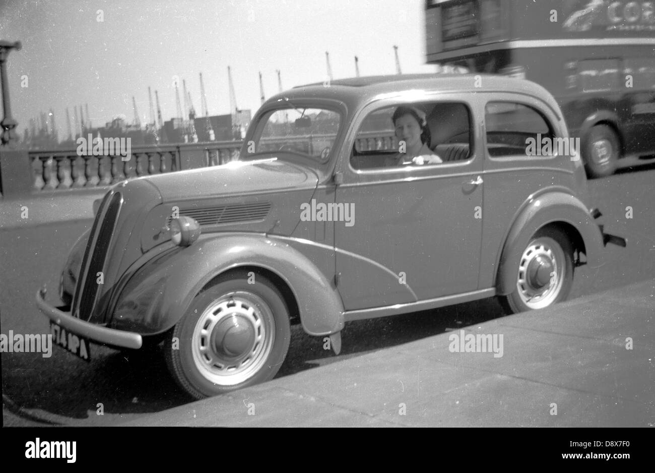 Image historique d'une dame assise dans le siège passager d'une voiture de l'époque garée à côté de la chaussée sur Tower Bridge à Londres, Angleterre, Royaume-Uni. Banque D'Images