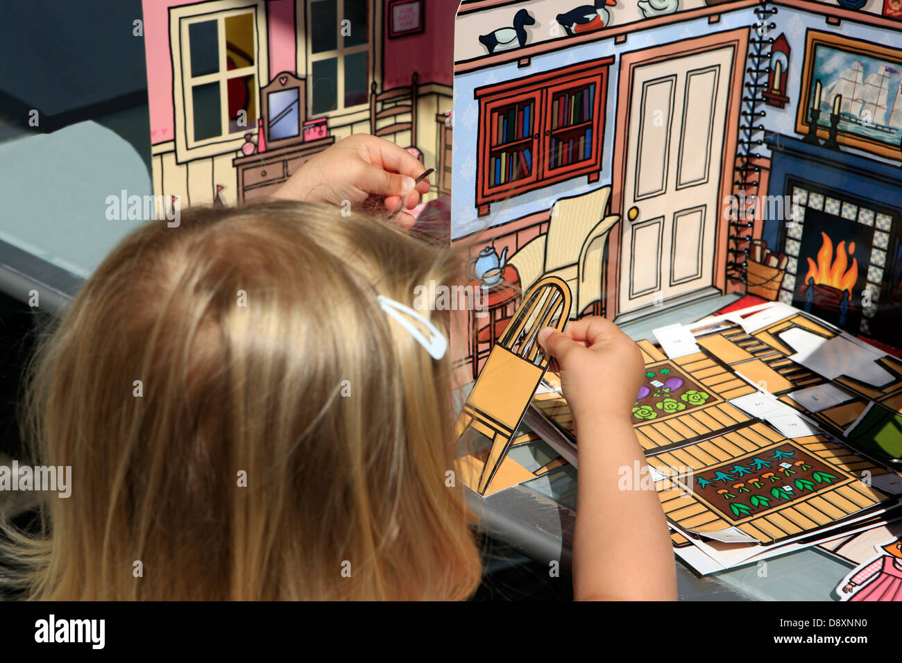 Jeune fille blonde jouant avec une maison de poupées pop up book Banque D'Images