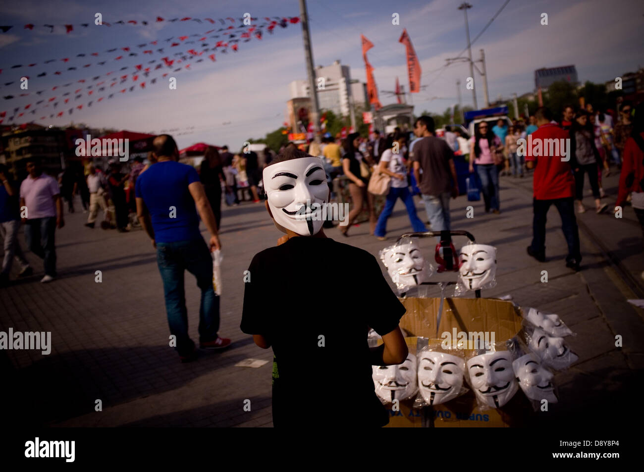 Istanbul, Turquie. 6 juin, 2013. Un garçon vend des masques anonyme sur la place Taksim. Après plusieurs jours de conflit, la Place Taksim à Istanbul était calme le 6 juin, avec les gens du camping et de personnes scandant des slogans contre le gouvernement. Crédit : Jordi Boixareu/Alamy Live News Banque D'Images