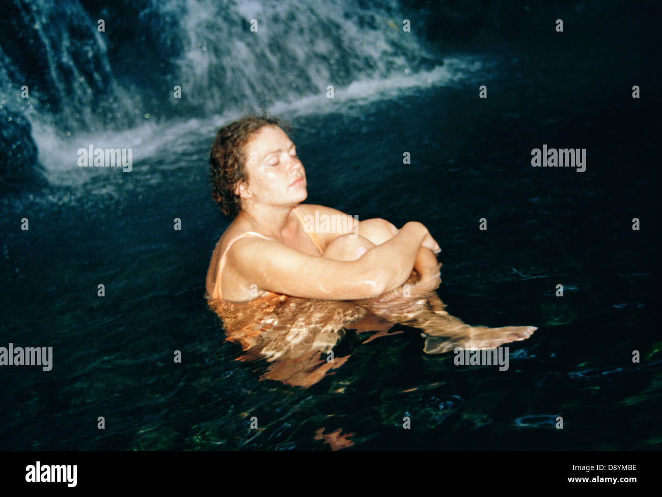 Femme assise par une cascade, les Îles Philippines. Banque D'Images